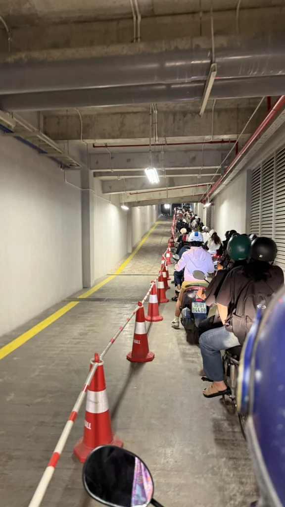 イオンモール フエの地下駐車場の出口通路。コーンとロープで区切られたレーンに、バイクが奥まで列をなして出庫を待っている