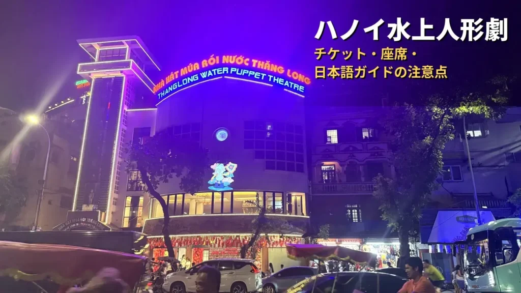 夜のタンロン水上人形劇場の外観。紫色にライトアップされた建物の上部に「THANGLONG WATER PUPPET THEATRE」の看板が光る