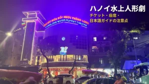夜のタンロン水上人形劇場の外観。紫色にライトアップされた建物の上部に「THANGLONG WATER PUPPET THEATRE」の看板が光る