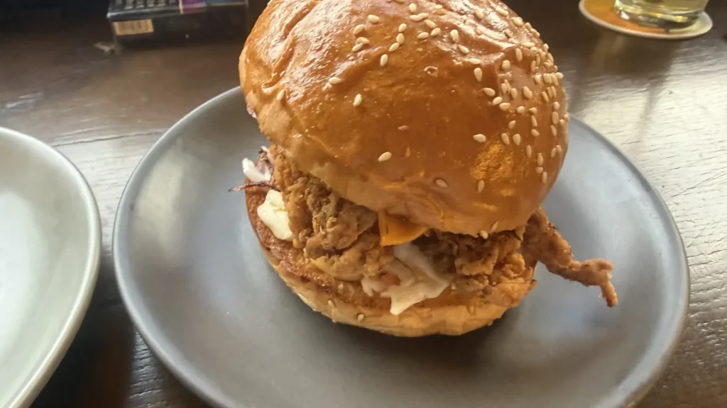 BiaCraftのバーガー。つやのあるゴマ付きバンズに揚げ物とコールスローが挟まっている