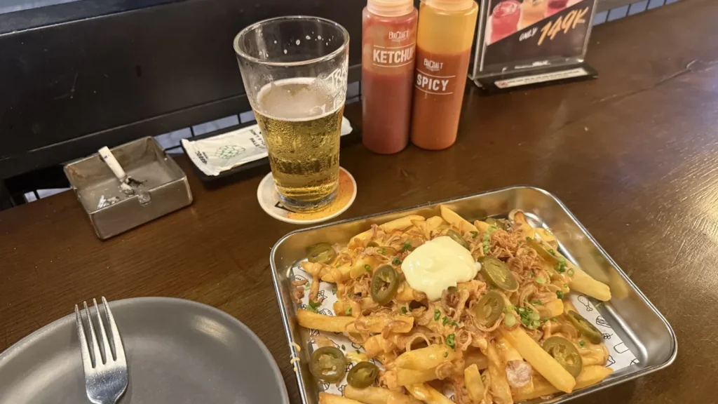 BiaCraftのローデッドフライ。チーズソース、ハラペーニョ、フライドオニオン、マヨネーズがトッピングされたポテトとクラフトビール
