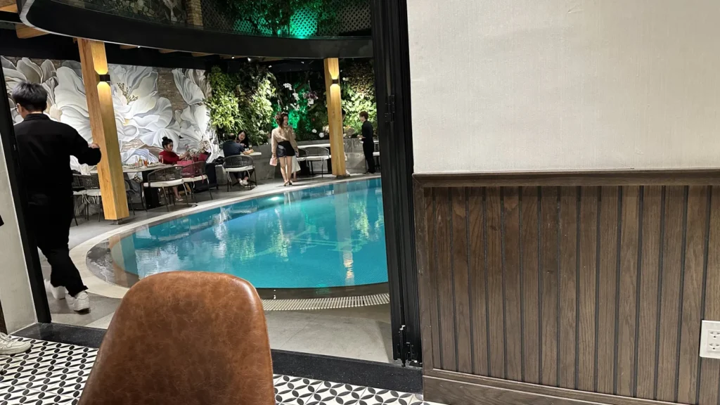 Steak Love The Villaの室内席から見たライトアップされたプールと、プールサイドのテラス席
